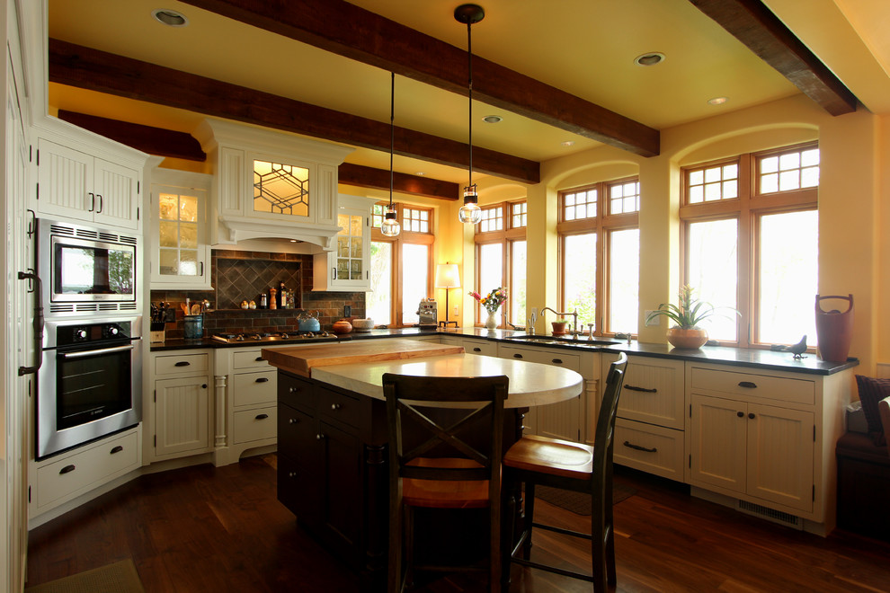 Eat-in kitchen - large cottage u-shaped medium tone wood floor eat-in kitchen idea in Other with a triple-bowl sink, beaded inset cabinets, white cabinets, granite countertops, multicolored backsplash, stone tile backsplash, paneled appliances and an island