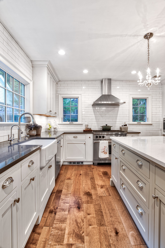 Kitchen pantry - mid-sized country u-shaped medium tone wood floor kitchen pantry idea in New York with a farmhouse sink, beaded inset cabinets, white cabinets, quartzite countertops, white backsplash, subway tile backsplash, stainless steel appliances, an island and black countertops