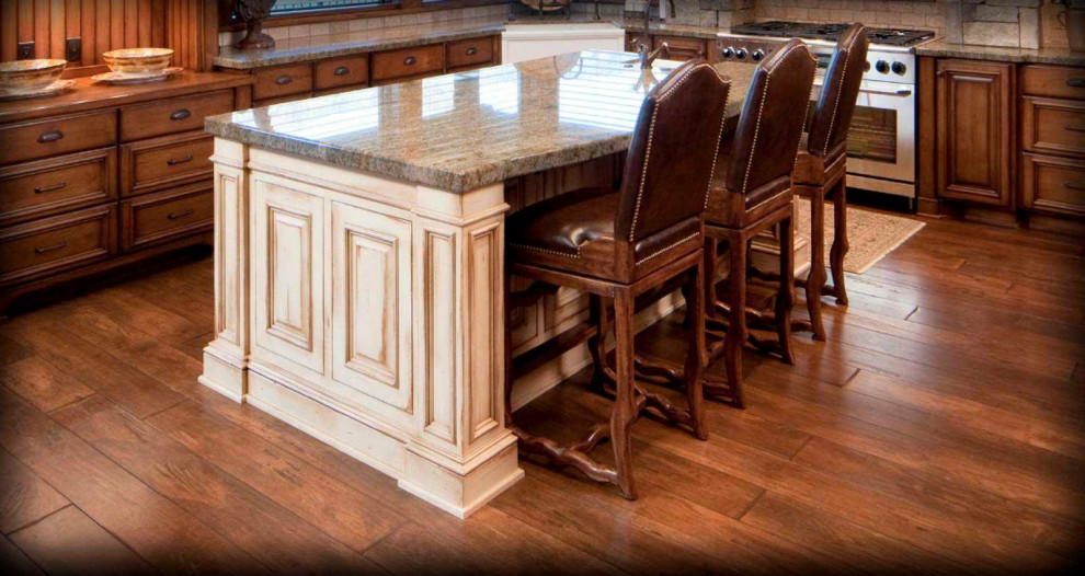 Modelo de cocinas en U rústico cerrado con fregadero sobremueble, armarios con paneles con relieve, puertas de armario de madera en tonos medios, encimera de cuarcita, salpicadero beige, salpicadero de piedra caliza, electrodomésticos de acero inoxidable, suelo de madera en tonos medios, una isla, suelo marrón y encimeras grises