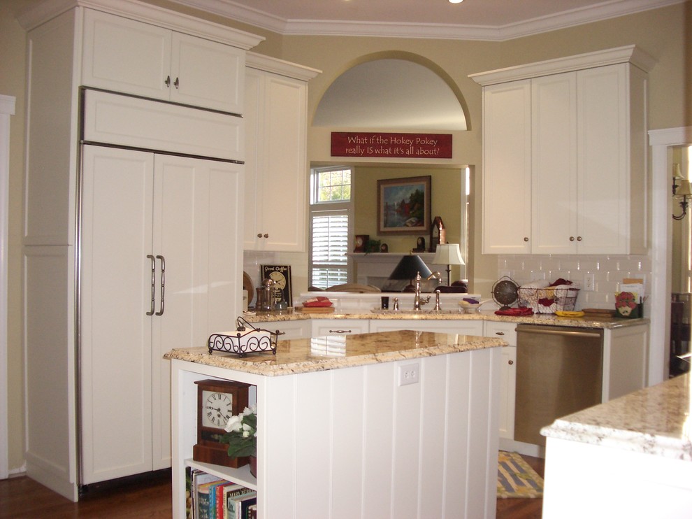 This is an example of a medium sized classic galley enclosed kitchen in Charlotte with a built-in sink, shaker cabinets, white cabinets, coloured appliances, dark hardwood flooring and an island.