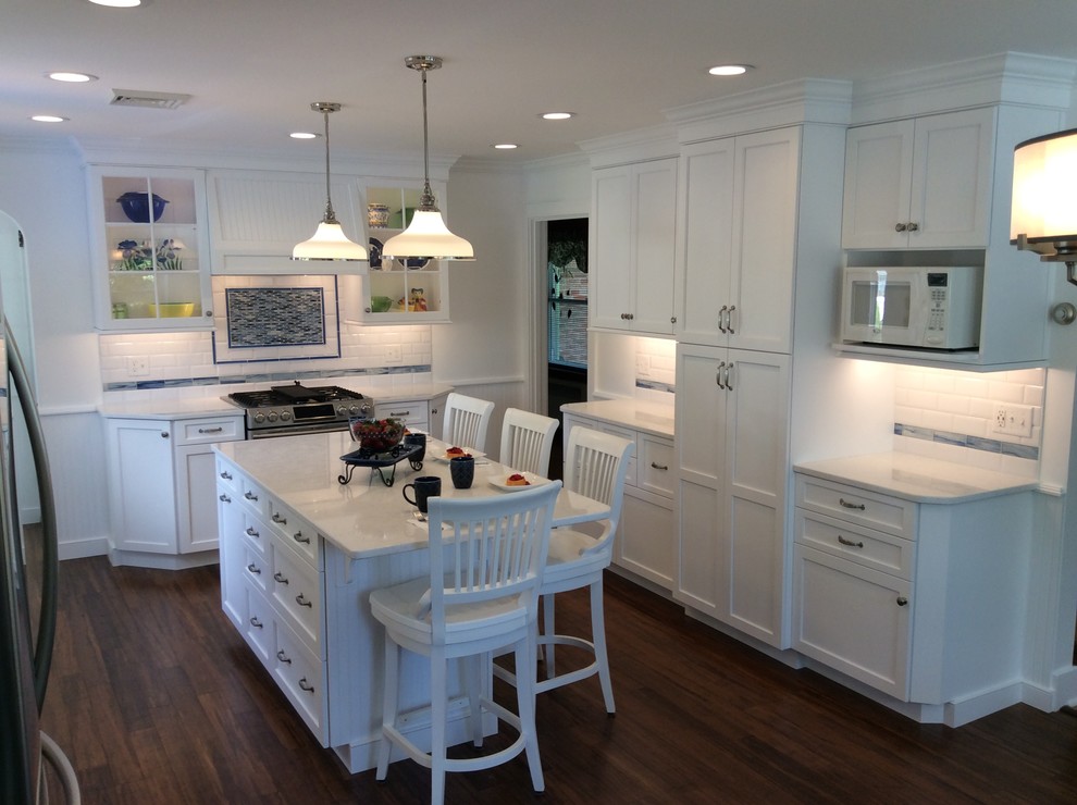 Eat-in kitchen - mid-sized transitional u-shaped bamboo floor eat-in kitchen idea in Other with a farmhouse sink, shaker cabinets, white cabinets, quartz countertops, white backsplash, porcelain backsplash, stainless steel appliances and an island