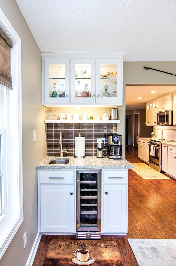 Example of a large transitional galley medium tone wood floor and brown floor enclosed kitchen design in Other with an undermount sink, white cabinets, quartzite countertops, white backsplash, stainless steel appliances, shaker cabinets, ceramic backsplash, a peninsula and multicolored countertops