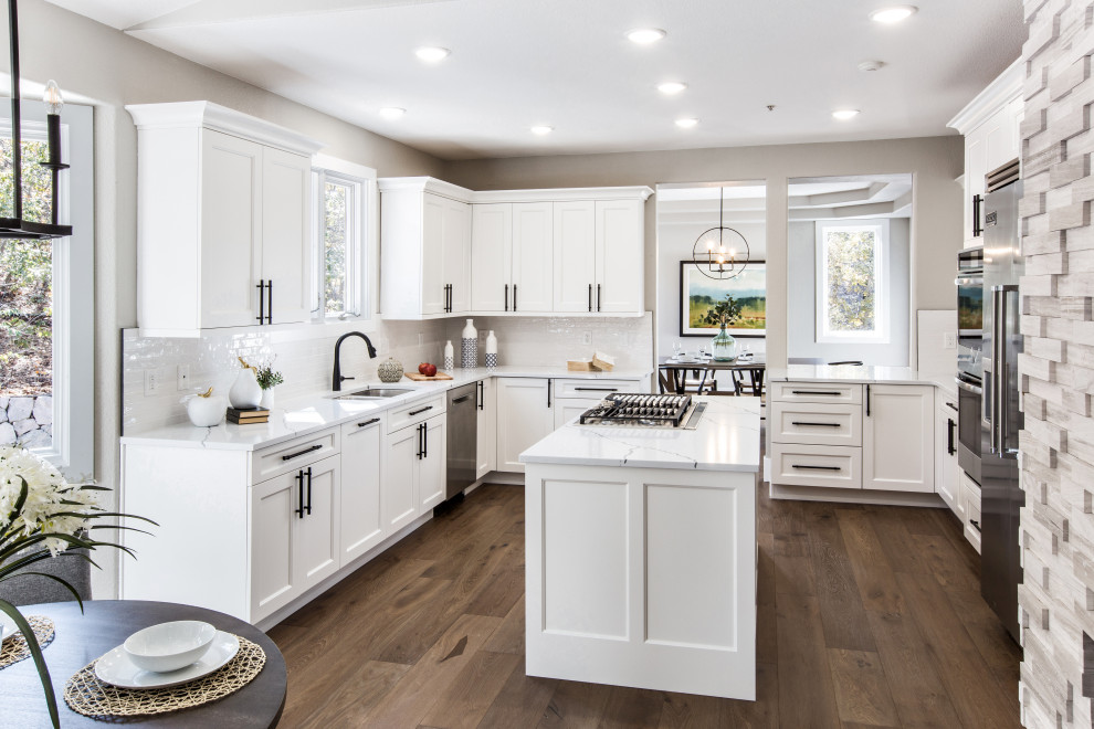Bild på ett mellanstort vintage vit vitt kök och matrum, med en undermonterad diskho, skåp i shakerstil, vita skåp, bänkskiva i kvarts, vitt stänkskydd, stänkskydd i tunnelbanekakel, rostfria vitvaror, mellanmörkt trägolv, en köksö och brunt golv