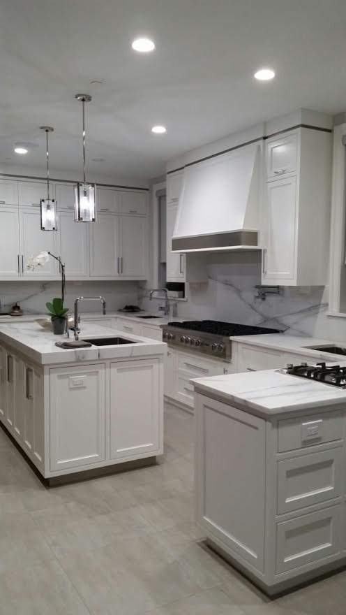 Inspiration for a large contemporary u-shaped kitchen in New York with a submerged sink, shaker cabinets, white cabinets, marble worktops, white splashback, stone slab splashback, stainless steel appliances and an island.