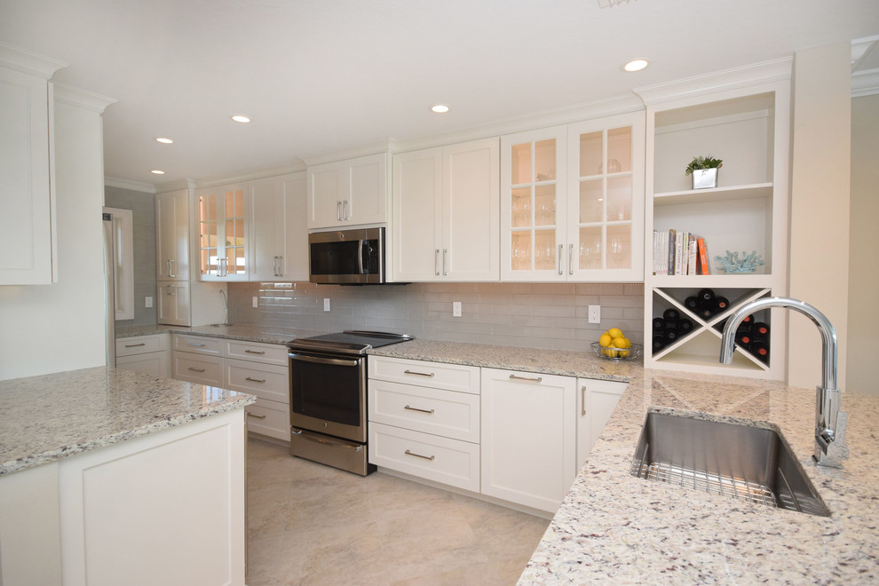 Example of a mid-sized transitional concrete floor and beige floor kitchen design in Tampa with an undermount sink, shaker cabinets, white cabinets, granite countertops, gray backsplash, subway tile backsplash, stainless steel appliances and an island