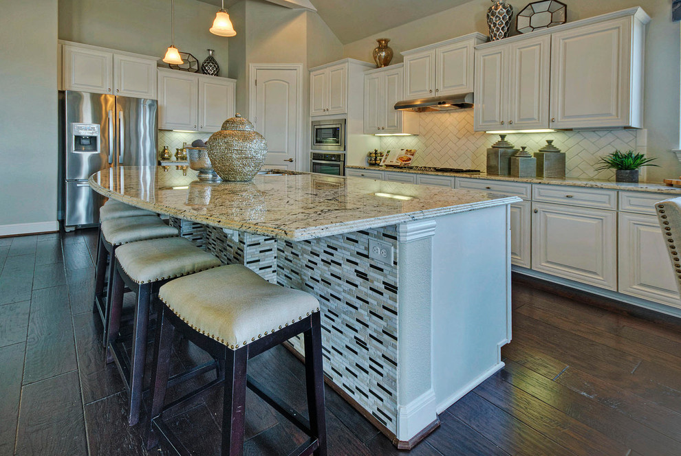 Bild på ett stort funkis kök, med en undermonterad diskho, luckor med upphöjd panel, vita skåp, granitbänkskiva, vitt stänkskydd, stänkskydd i tunnelbanekakel, rostfria vitvaror, mörkt trägolv och en köksö
