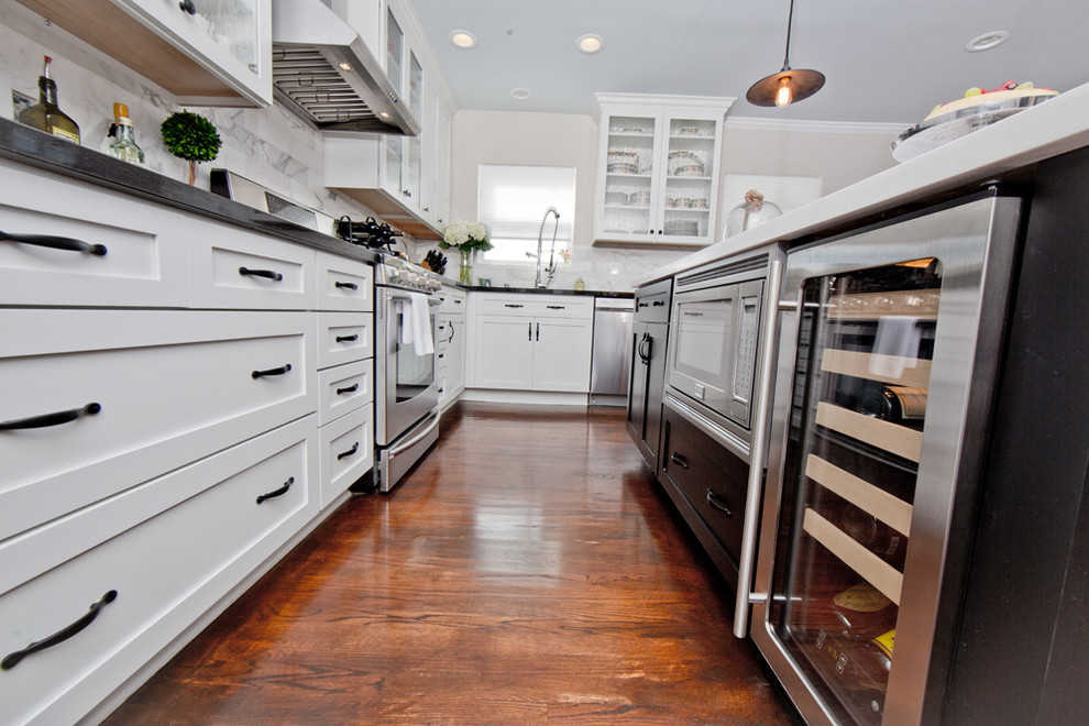 Bild på ett mellanstort funkis kök, med en undermonterad diskho, luckor med infälld panel, vita skåp, granitbänkskiva, grått stänkskydd, stänkskydd i stenkakel, rostfria vitvaror, mörkt trägolv och en köksö