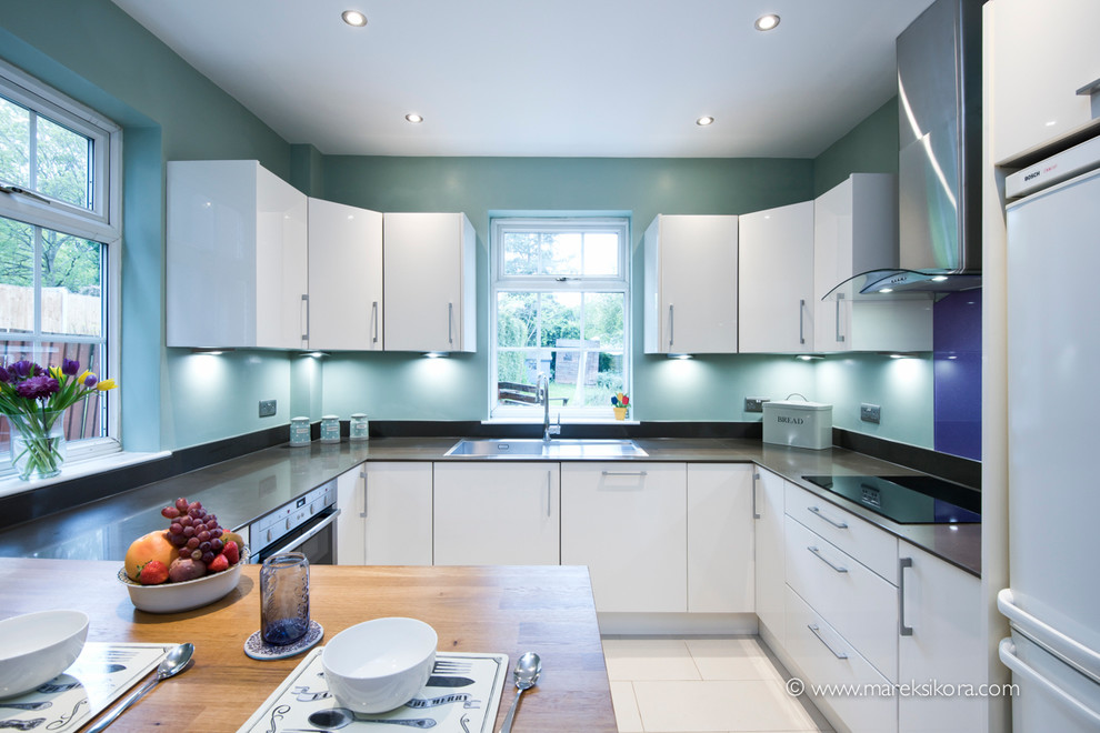 This is an example of a contemporary u-shaped kitchen/diner in London with flat-panel cabinets, white cabinets and no island.