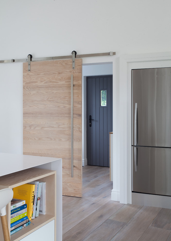 Exempel på ett modernt kök, med en undermonterad diskho, släta luckor, vita skåp, bänkskiva i kvartsit, ljust trägolv och en köksö