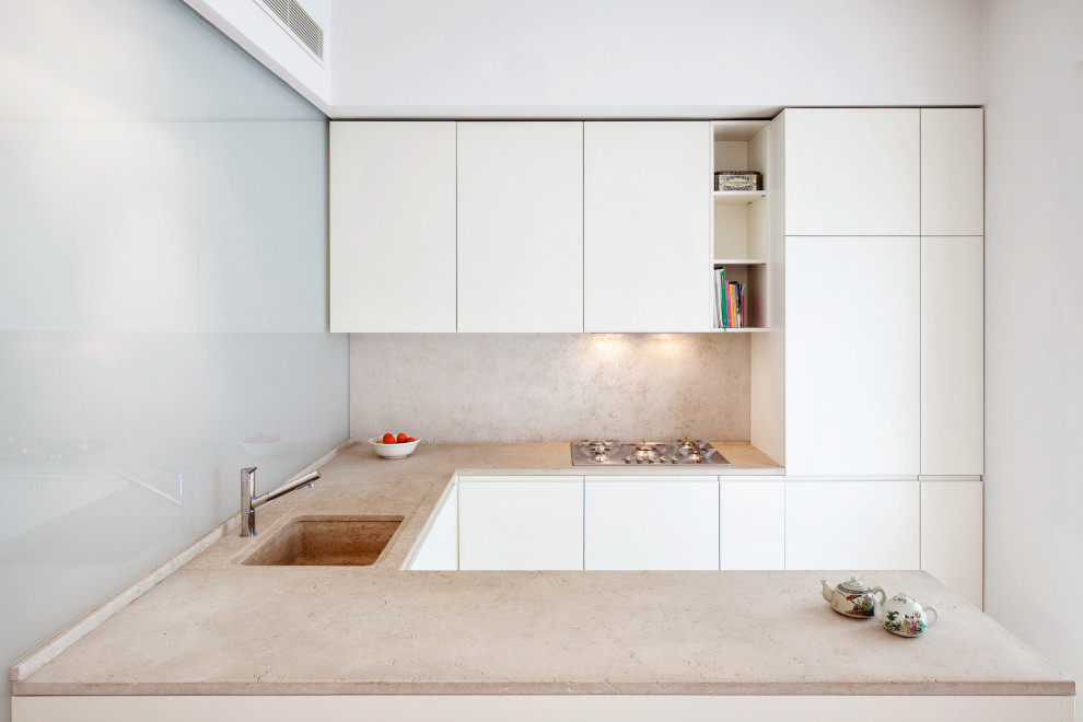 Contemporary u-shaped kitchen in New York with a submerged sink, flat-panel cabinets, white cabinets, beige splashback, stainless steel appliances, a breakfast bar and beige worktops.