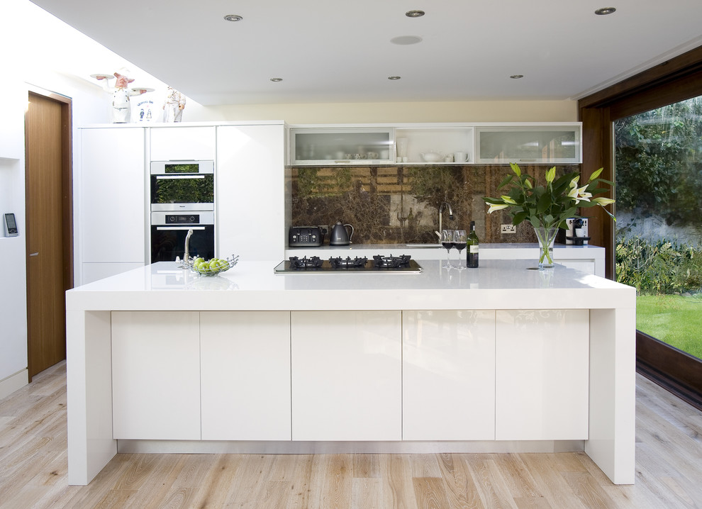Photo of a contemporary galley kitchen in Other with flat-panel cabinets, white cabinets, brown splashback and stone slab splashback.