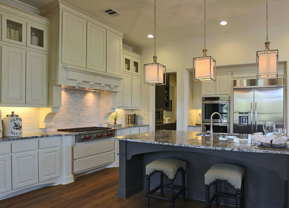 Example of a large classic l-shaped medium tone wood floor open concept kitchen design in Austin with an undermount sink, raised-panel cabinets, white cabinets, granite countertops, multicolored backsplash, stainless steel appliances and an island