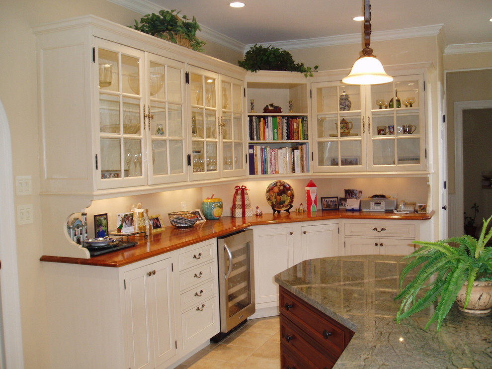 Esempio di una cucina chic di medie dimensioni con ante con finitura invecchiata, elettrodomestici in acciaio inossidabile, ante di vetro, top in legno, paraspruzzi bianco e pavimento in gres porcellanato