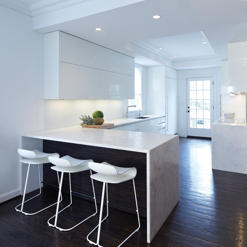 Large minimalist galley dark wood floor and brown floor eat-in kitchen photo in DC Metro with an integrated sink, flat-panel cabinets, white cabinets, marble countertops, white backsplash, stone slab backsplash and paneled appliances