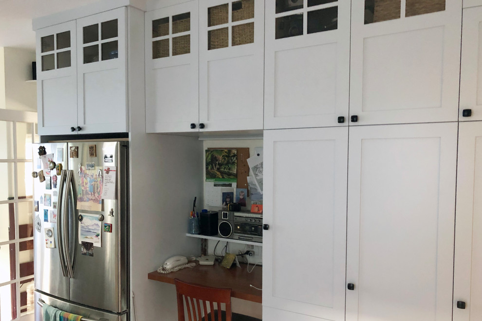 Medium sized classic u-shaped kitchen/diner in Boston with a belfast sink, shaker cabinets, white cabinets, white splashback, metro tiled splashback, stainless steel appliances, medium hardwood flooring, brown floors and black worktops.