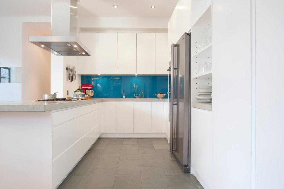 Moderne Küche in U-Form mit flächenbündigen Schrankfronten, weißen Schränken, Küchenrückwand in Blau, Glasrückwand, Küchengeräten aus Edelstahl und Halbinsel in London