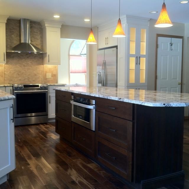 Medium sized classic l-shaped kitchen/diner in New York with a submerged sink, shaker cabinets, dark wood cabinets, engineered stone countertops, grey splashback, stone tiled splashback, stainless steel appliances, medium hardwood flooring and an island.