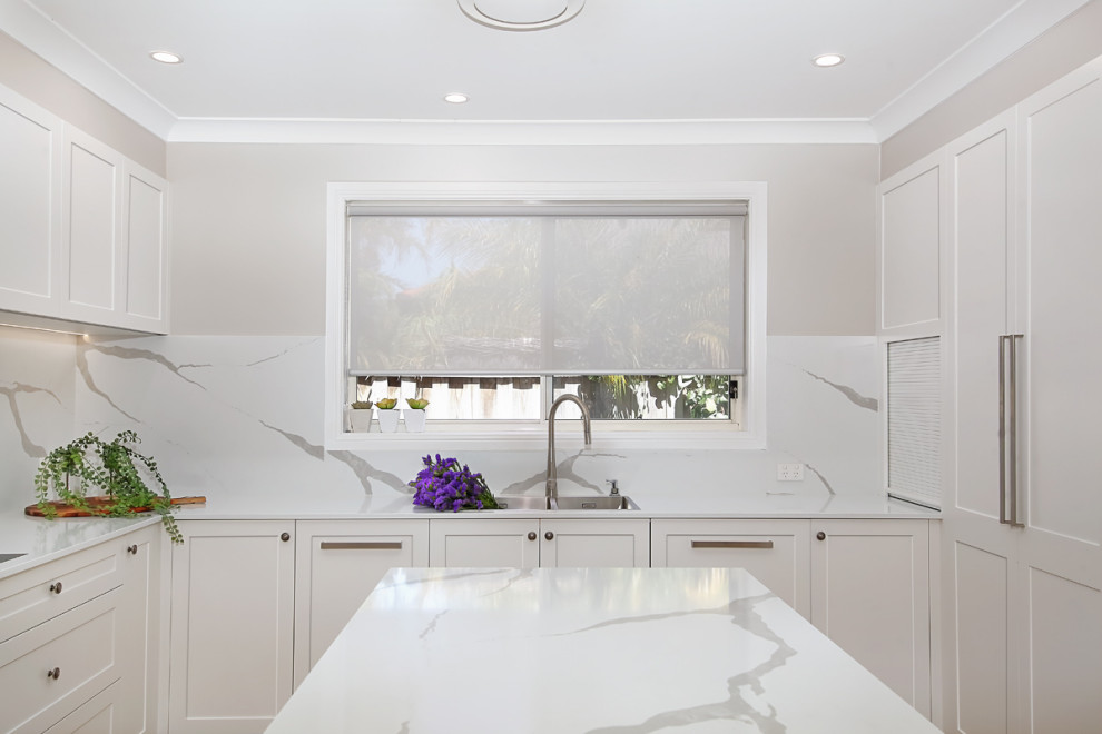 Eat-in kitchen - large modern u-shaped dark wood floor and brown floor eat-in kitchen idea in Sydney with an integrated sink, raised-panel cabinets, white cabinets, quartz countertops, white backsplash, stone slab backsplash, paneled appliances, an island and white countertops