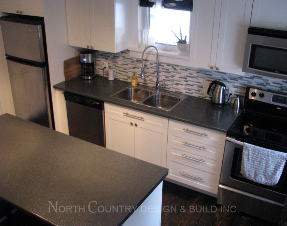 Photo of a medium sized contemporary l-shaped enclosed kitchen in Toronto with a double-bowl sink, shaker cabinets, white cabinets, laminate countertops, blue splashback, glass tiled splashback, stainless steel appliances, dark hardwood flooring and an island.