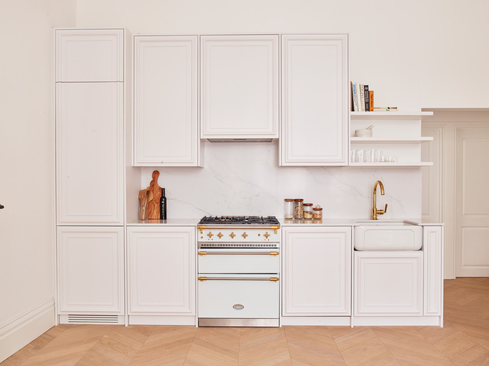 Idéer för att renovera ett litet funkis linjärt kök med öppen planlösning, med en rustik diskho, luckor med profilerade fronter, vita skåp, marmorbänkskiva, vitt stänkskydd, stänkskydd i marmor, vita vitvaror och ljust trägolv
