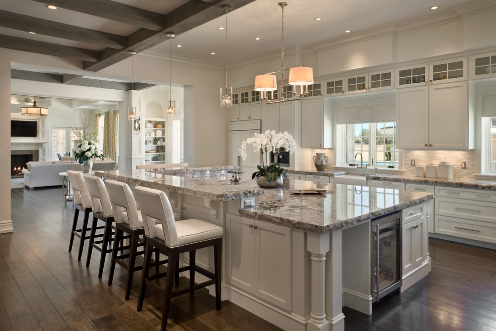 Eat-in kitchen - traditional l-shaped dark wood floor eat-in kitchen idea in Orlando with a farmhouse sink, recessed-panel cabinets, white cabinets, granite countertops, gray backsplash, glass sheet backsplash, stainless steel appliances and an island