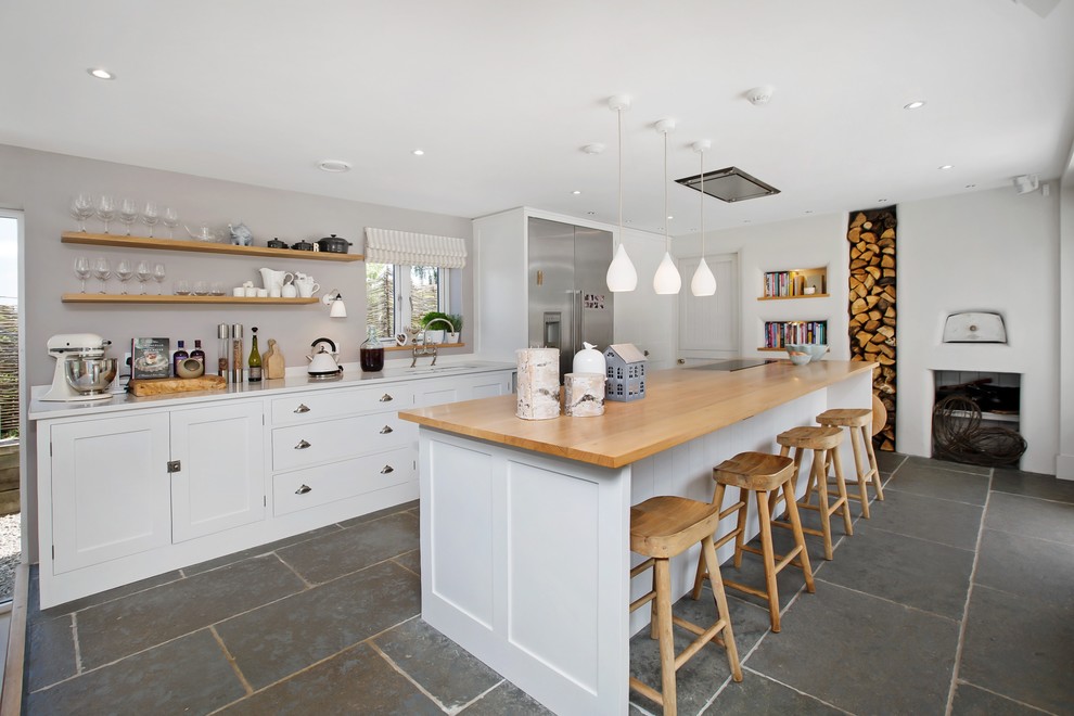 Design ideas for a coastal kitchen in Devon with a submerged sink, shaker cabinets, white cabinets, wood worktops, stainless steel appliances, an island, grey floors, beige worktops and slate flooring.