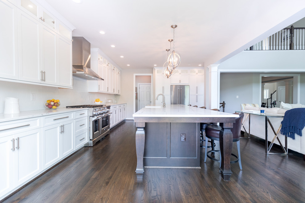 Inspiration for a large contemporary single-wall dark wood floor eat-in kitchen remodel in DC Metro with a farmhouse sink, recessed-panel cabinets, white cabinets, quartzite countertops, white backsplash, ceramic backsplash, stainless steel appliances and an island