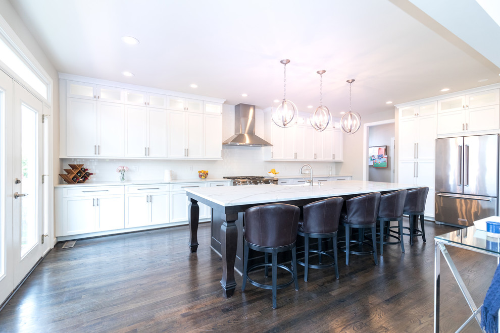 Large trendy single-wall dark wood floor eat-in kitchen photo in DC Metro with a farmhouse sink, recessed-panel cabinets, quartzite countertops, white backsplash, ceramic backsplash, stainless steel appliances, an island and white cabinets