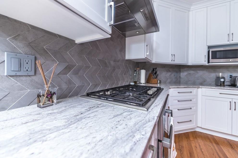 Example of a transitional medium tone wood floor eat-in kitchen design in DC Metro with a single-bowl sink, shaker cabinets, white cabinets, granite countertops, gray backsplash, stone tile backsplash, stainless steel appliances and a peninsula