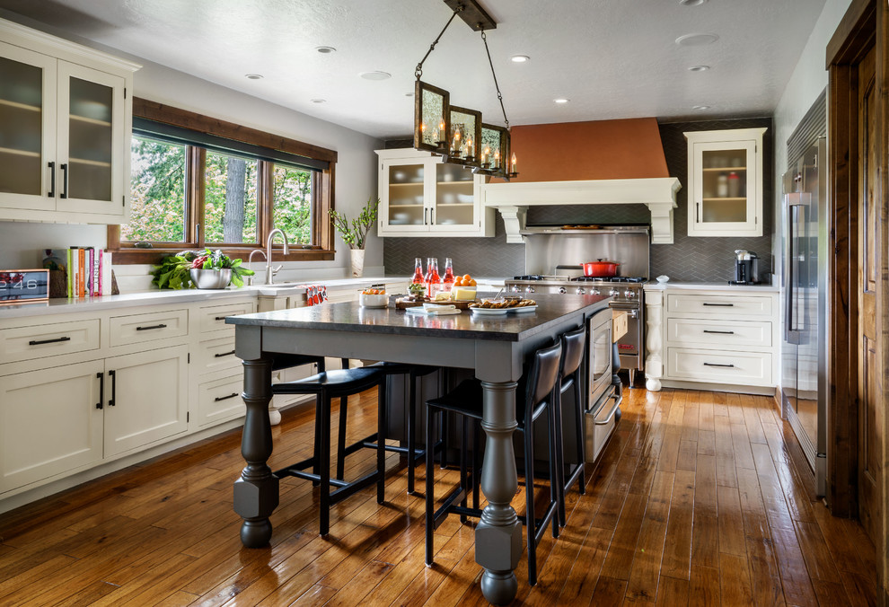 Large elegant u-shaped medium tone wood floor and brown floor kitchen photo in Portland with an undermount sink, white cabinets, quartz countertops, gray backsplash, glass tile backsplash, stainless steel appliances, an island and shaker cabinets