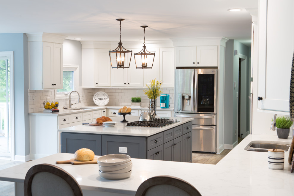 Exempel på ett stort klassiskt flerfärgad flerfärgat kök, med en undermonterad diskho, luckor med infälld panel, vita skåp, bänkskiva i kvartsit, vitt stänkskydd, stänkskydd i tunnelbanekakel, rostfria vitvaror, vinylgolv, flera köksöar och brunt golv