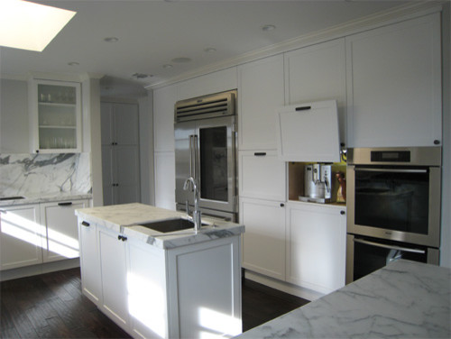 Large modern u-shaped kitchen in Los Angeles with a submerged sink, shaker cabinets, white cabinets, marble worktops, stone slab splashback, stainless steel appliances and dark hardwood flooring.