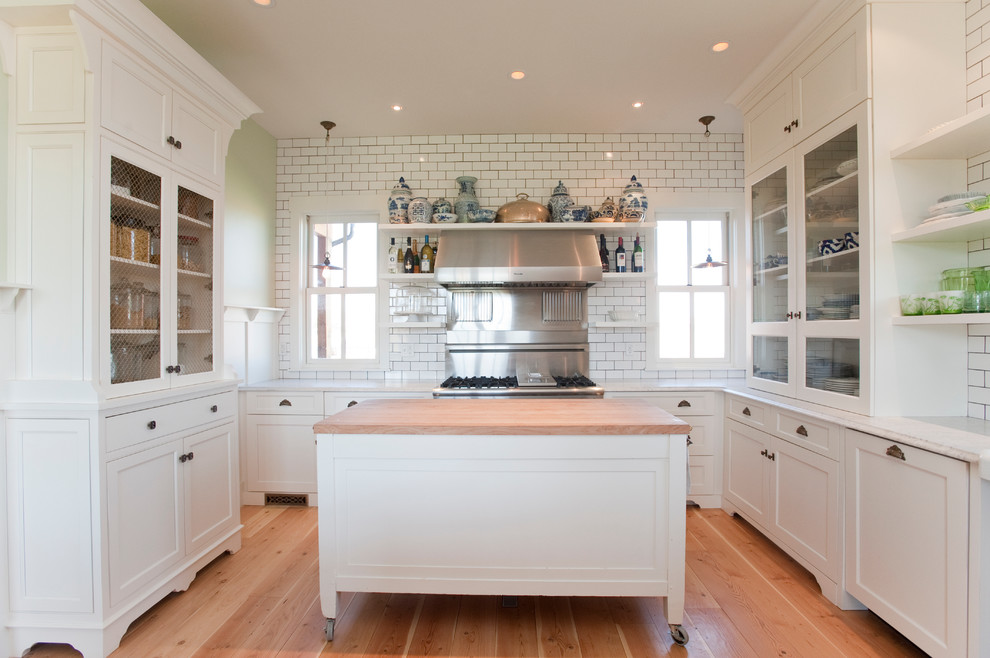 Foto de cocina de estilo de casa de campo con armarios con paneles lisos, salpicadero blanco, salpicadero de azulejos tipo metro, electrodomésticos de acero inoxidable y puertas de armario blancas