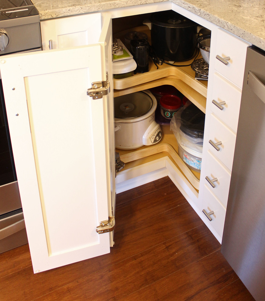 Photo of a small classic u-shaped kitchen/diner in Cleveland with a submerged sink, shaker cabinets, white cabinets, engineered stone countertops, grey splashback, metro tiled splashback, stainless steel appliances, medium hardwood flooring, an island, brown floors and beige worktops.