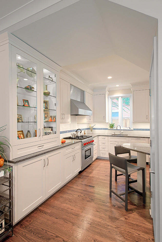 Eat-in kitchen - mid-sized transitional l-shaped medium tone wood floor, brown floor and vaulted ceiling eat-in kitchen idea in Chicago with an undermount sink, shaker cabinets, white cabinets, white backsplash, subway tile backsplash, stainless steel appliances, an island, quartz countertops and gray countertops