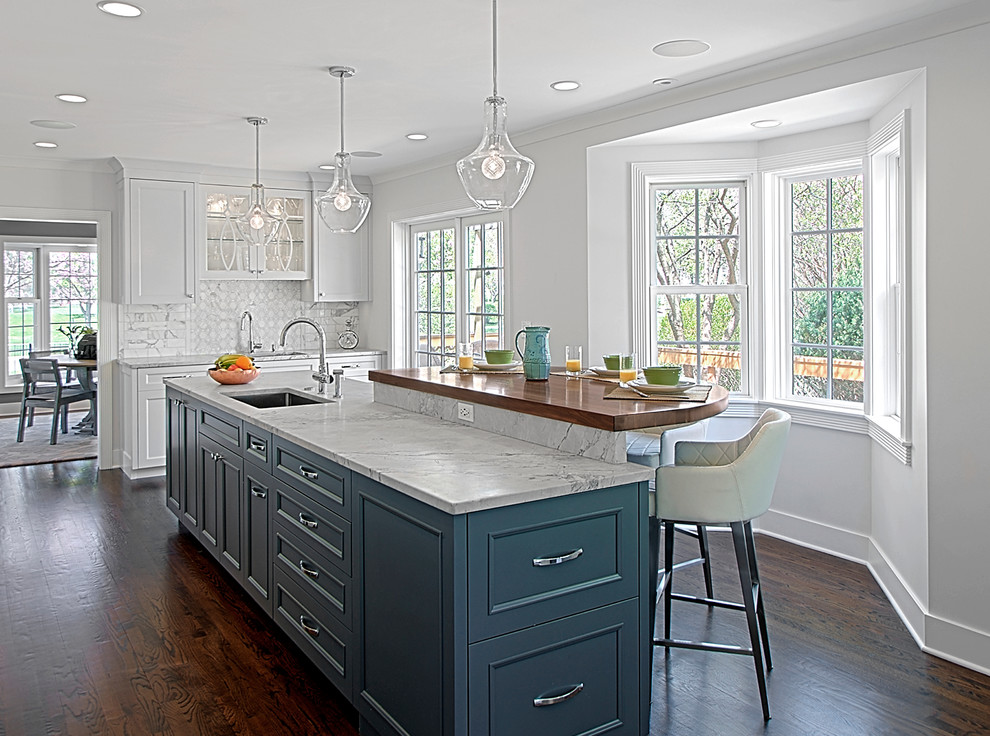 Inspiration for a transitional dark wood floor kitchen remodel in Chicago with recessed-panel cabinets, white cabinets, white backsplash, stone tile backsplash and an island