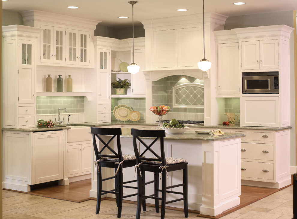 Mid-sized elegant l-shaped light wood floor kitchen photo in Chicago with a farmhouse sink, shaker cabinets, white cabinets, green backsplash, subway tile backsplash, stainless steel appliances and an island