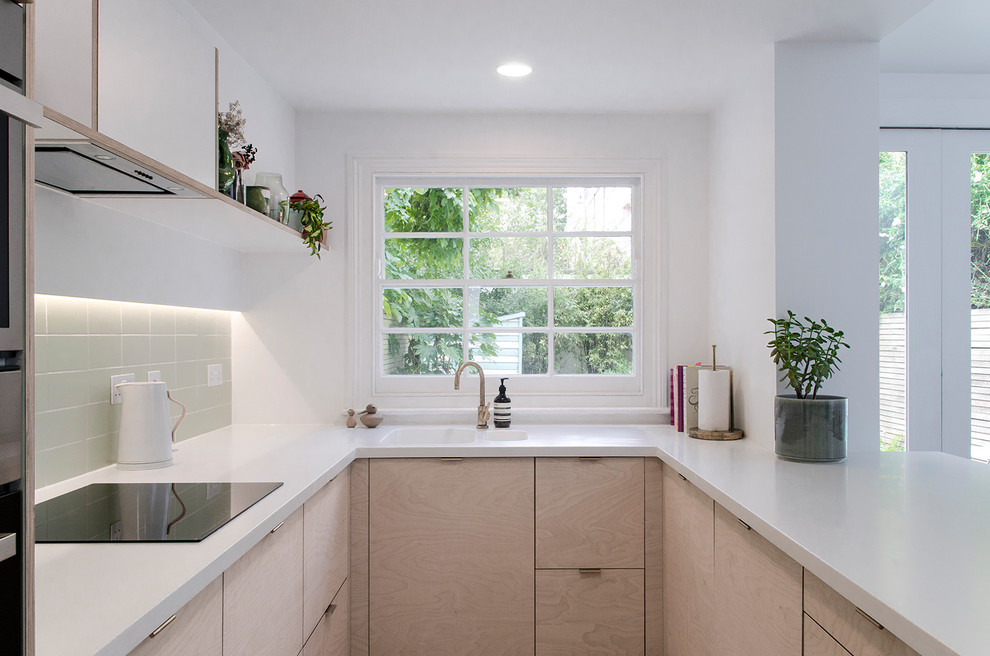 Modern inredning av ett mellanstort vit vitt kök, med en nedsänkt diskho, släta luckor, skåp i ljust trä, bänkskiva i koppar, grönt stänkskydd, stänkskydd i keramik, rostfria vitvaror, vinylgolv, en halv köksö och grått golv