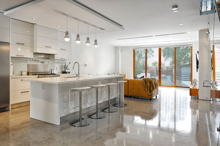 Modelo de cocina comedor minimalista con electrodomésticos de acero inoxidable, suelo de cemento, una isla y suelo gris