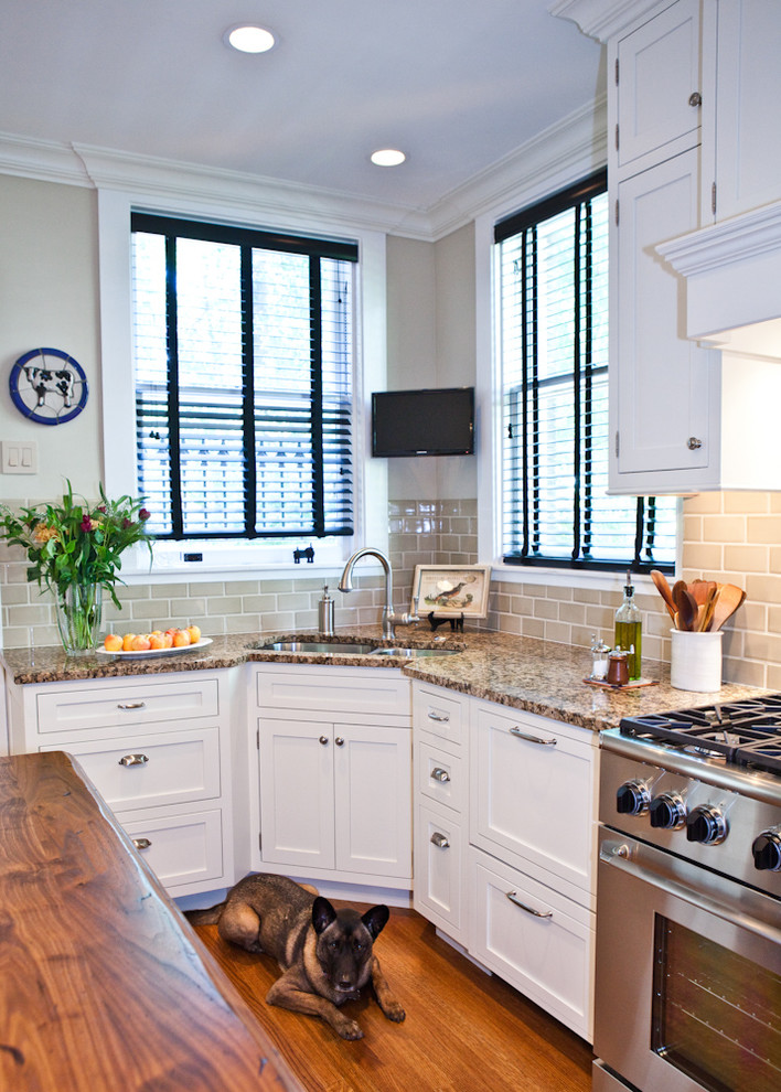 Inspiration for a mid-sized timeless l-shaped medium tone wood floor enclosed kitchen remodel in St Louis with an undermount sink, recessed-panel cabinets, white cabinets, granite countertops, beige backsplash, subway tile backsplash, paneled appliances and an island