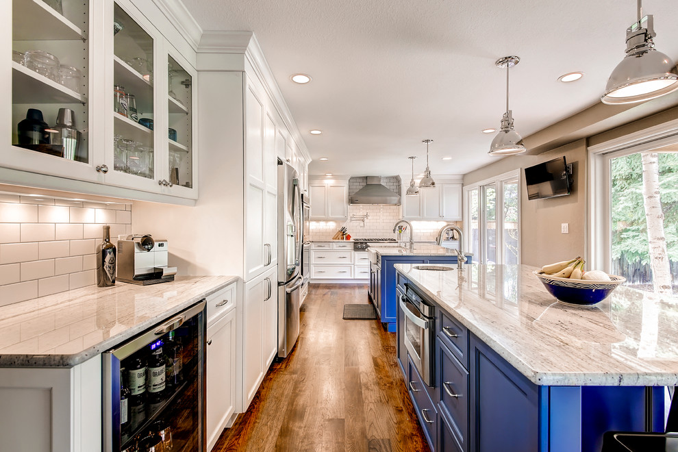 Photo of a large traditional kitchen/diner in Raleigh with a belfast sink, shaker cabinets, blue cabinets, white splashback, metro tiled splashback, stainless steel appliances, multiple islands and medium hardwood flooring.