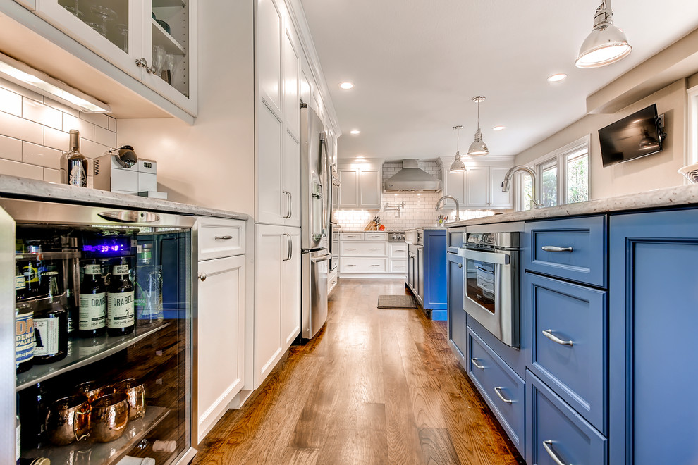 Eat-in kitchen - large transitional l-shaped eat-in kitchen idea in Raleigh with a farmhouse sink, shaker cabinets, blue cabinets, white backsplash, subway tile backsplash, stainless steel appliances and two islands