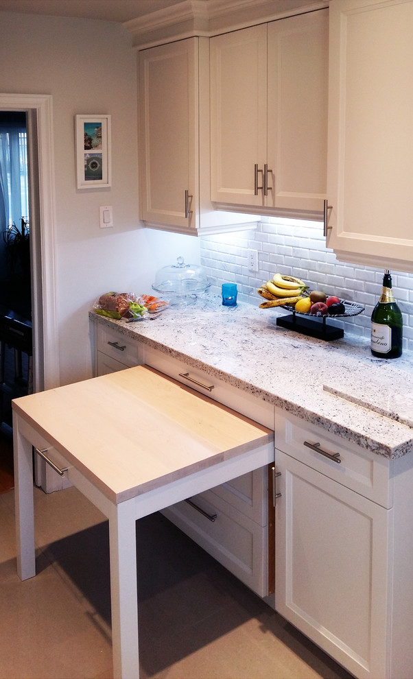 Photo of a traditional single-wall enclosed kitchen in Toronto with recessed-panel cabinets, white cabinets, granite worktops, white splashback, stone tiled splashback and light hardwood flooring.
