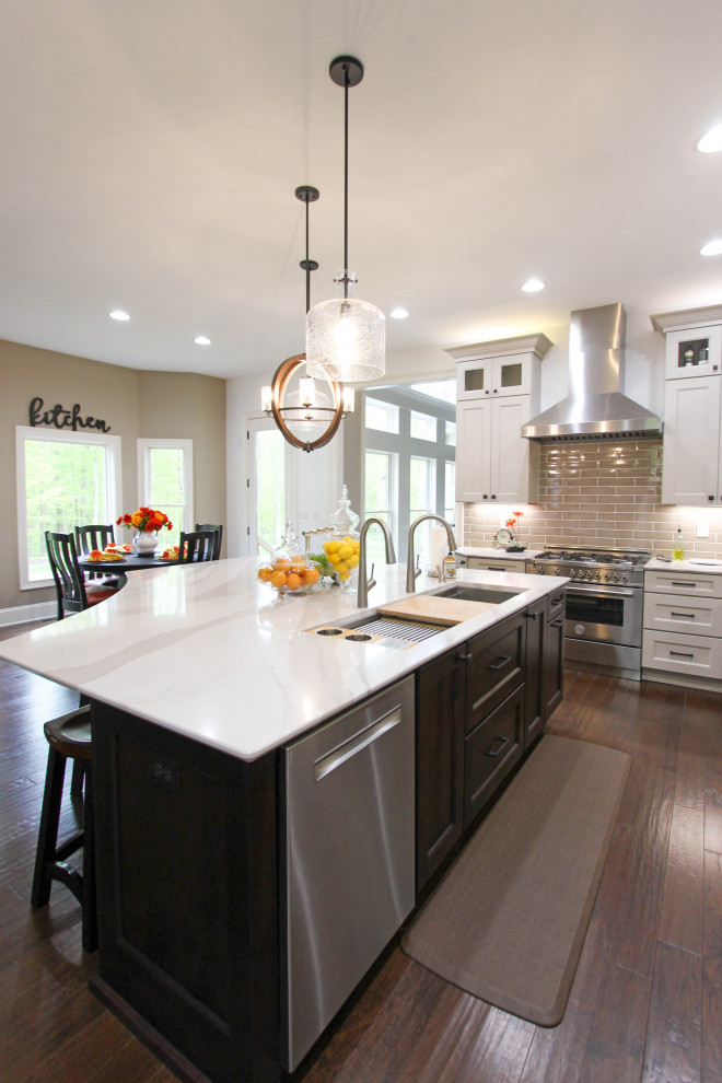 Inspiration for a large transitional galley eat-in kitchen remodel in Cleveland with an undermount sink, raised-panel cabinets, white cabinets, quartz countertops, brown backsplash, glass tile backsplash, stainless steel appliances, an island and white countertops