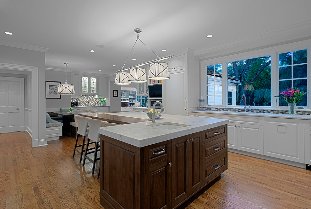 Inspiration for a large transitional u-shaped medium tone wood floor and brown floor eat-in kitchen remodel in Chicago with an undermount sink, raised-panel cabinets, white cabinets, quartzite countertops, multicolored backsplash, mosaic tile backsplash, an island and white countertops