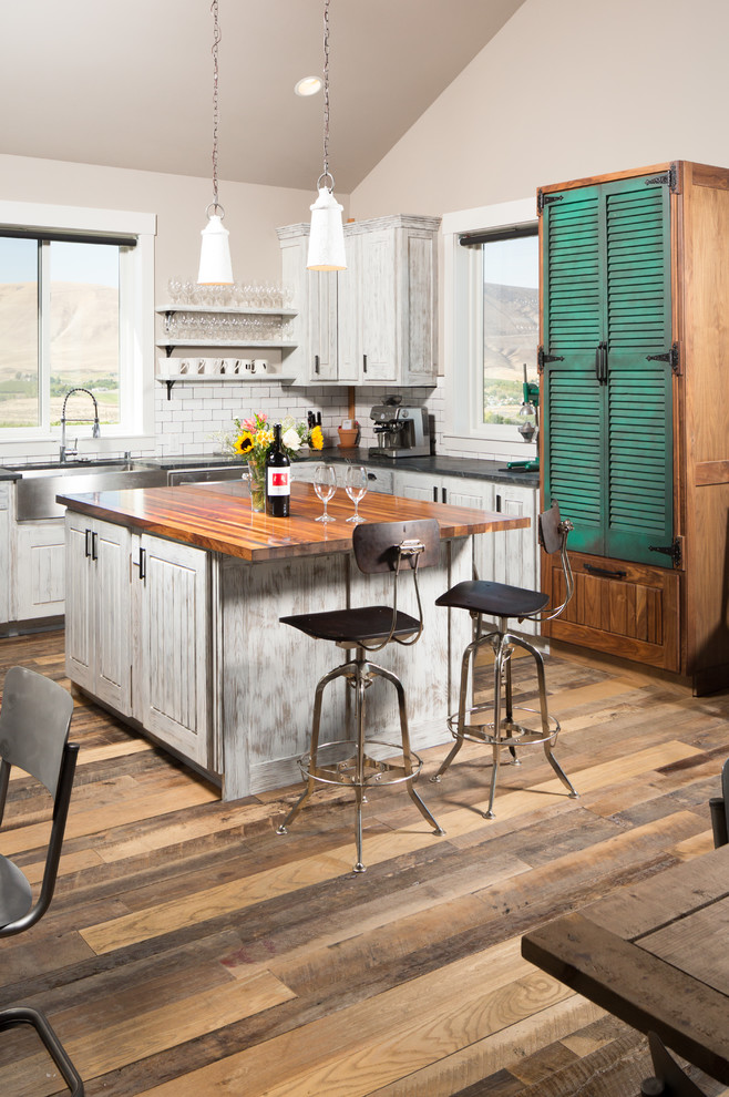Exempel på ett stort lantligt kök, med en rustik diskho, luckor med profilerade fronter, vita skåp, marmorbänkskiva, vitt stänkskydd, stänkskydd i tunnelbanekakel, rostfria vitvaror, målat trägolv och en köksö