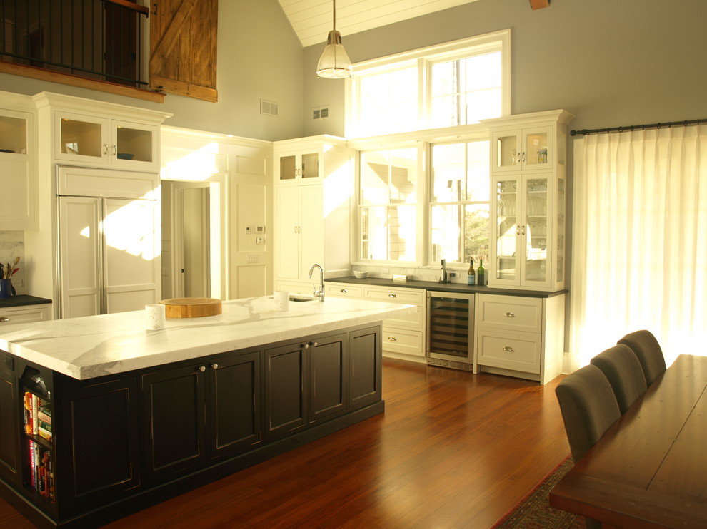 Mid-sized trendy u-shaped dark wood floor and brown floor eat-in kitchen photo in New York with a farmhouse sink, recessed-panel cabinets, white cabinets, solid surface countertops, white backsplash, paneled appliances, an island and marble backsplash