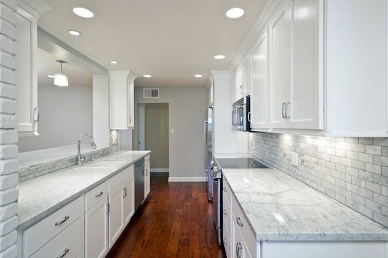 Kitchen - mid-sized transitional galley medium tone wood floor kitchen idea in New York with an undermount sink, white cabinets and stainless steel appliances