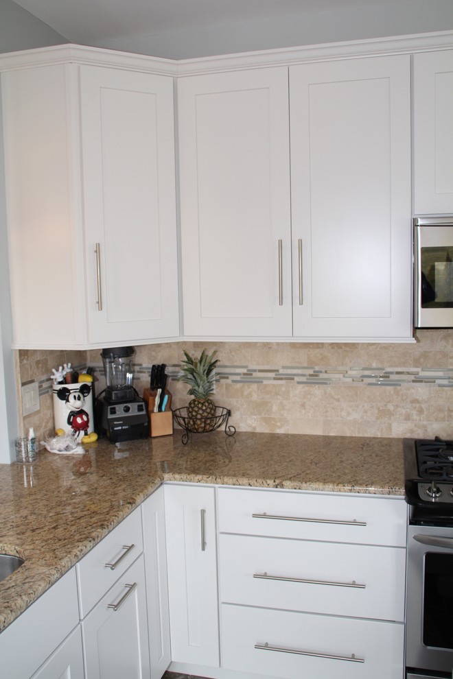 Photo of a small classic l-shaped kitchen/diner in Philadelphia with white cabinets, a submerged sink, shaker cabinets, granite worktops, beige splashback, porcelain splashback, stainless steel appliances, travertine flooring and an island.
