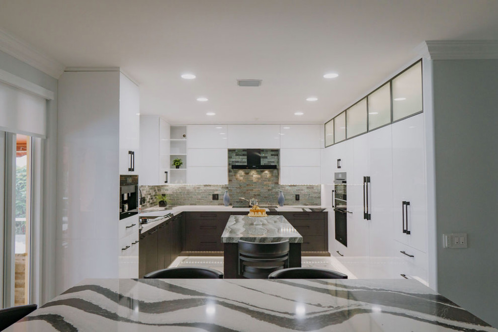 Inspiration for a large contemporary u-shaped open plan kitchen in Miami with a submerged sink, flat-panel cabinets, white cabinets, engineered stone countertops, metallic splashback, glass tiled splashback, black appliances, porcelain flooring, an island, white floors and multicoloured worktops.